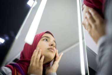 Müslüman güzel kız aynaya bakıyor yüz derisini kontrol ediyor