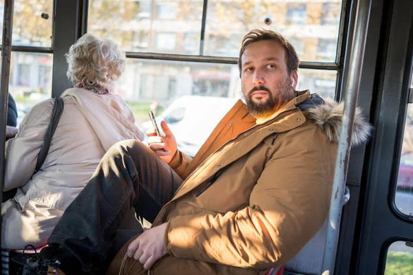Mannen i kollektivtrafiken sitter med smartphone lyssnar på musik — Stockfoto