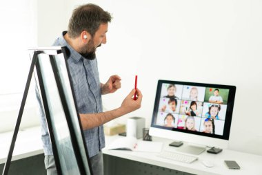 Erkek öğretmen okul çocuklarıyla çevrimiçi konferans yapıyor.