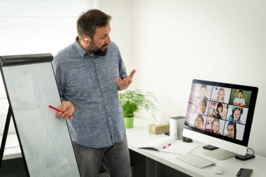 Erkek öğretmen okul çocuklarıyla çevrimiçi konferans yapıyor.