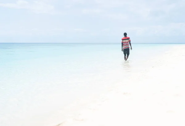 Zwarte Afrikaanse jongeman wandelen op tropisch strand — Stockfoto