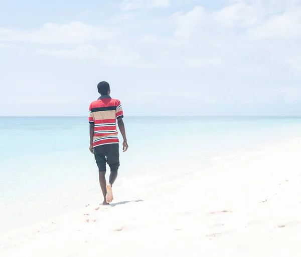 Молодий чорношкірий чоловік, що ходить по тропічному пляжу. — стокове фото