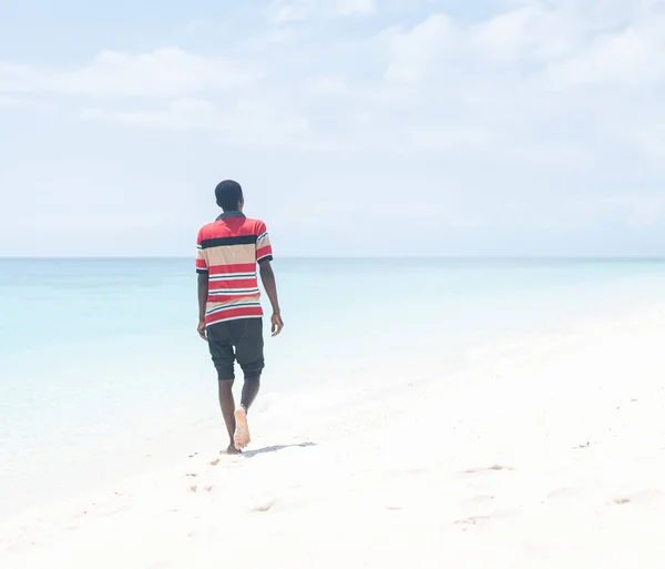 Preto jovem africano caminhando na praia tropical Fotos De Bancos De Imagens