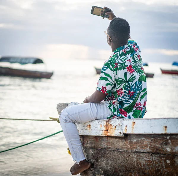 Jovem negro sentado no barco tirando selfie — Fotografia de Stock