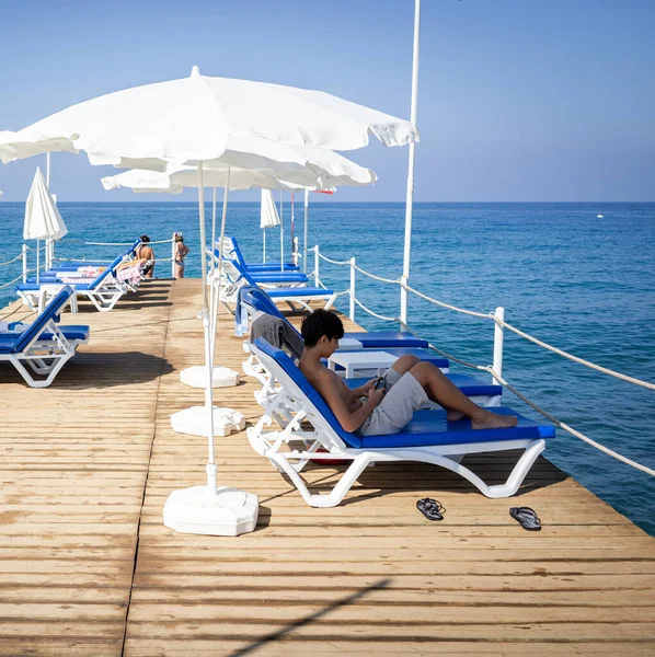 Teenage boy sitting on pier chair and enjoying summer — Stock Photo, Image