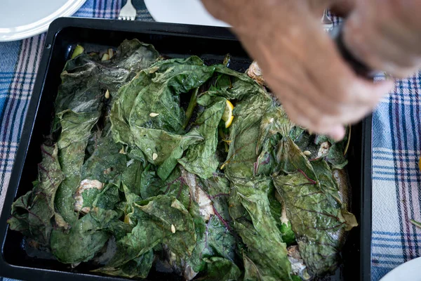 Preparing delicious food with fish and green leaves — Stock Photo, Image