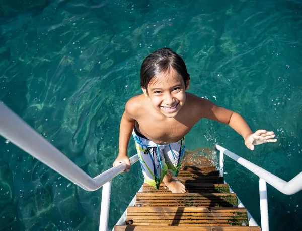 Little child climbing on sea pier ladder — Stock Photo, Image