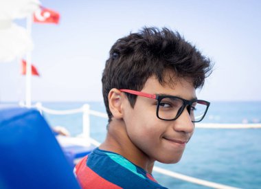 Genç çocuk iskelede oturuyor ve yazın tadını çıkarıyor.