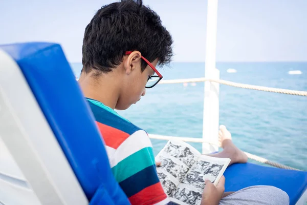 Genç çocuk iskelede oturuyor ve yazın tadını çıkarıyor. Telifsiz Stok Fotoğraflar