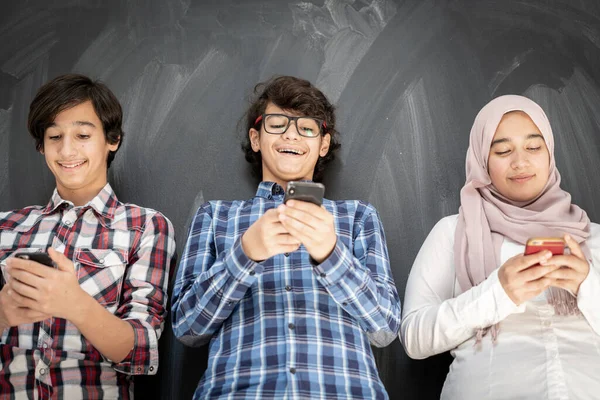 Group of multy ethnic kids in classroom with smartphones — Stock Photo, Image