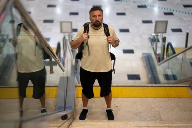 Orta yaşlı, sakallı bir adam seyahat ediyor. Havaalanında yolunu bulmaya çalışıyor. Yüksek kalite fotoğraf