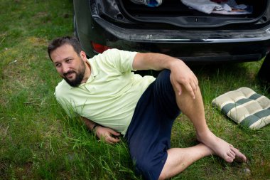 Kamp molası sırasında yeşil çimlere uzanmış rahat bir adam. Yüksek kalite fotoğraf