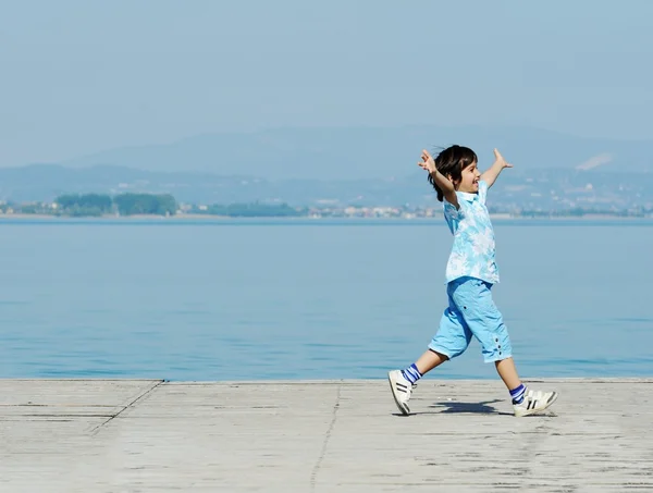 Малюк біжить на причалі озера — стокове фото
