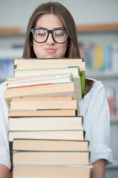 Jovem feliz na biblioteca da faculdade segurando pilha de livros — Fotografia de Stock