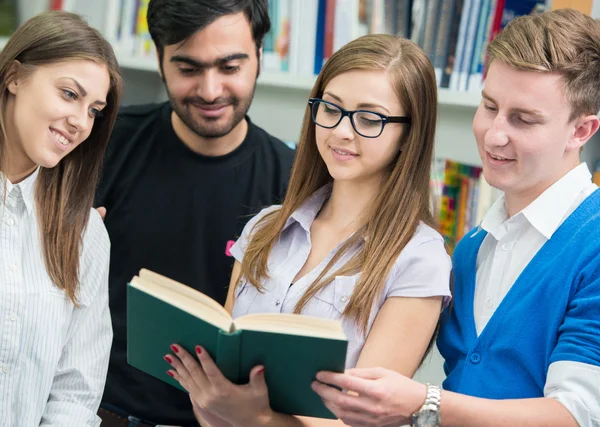 Jovens estudantes felizes estudando na biblioteca da faculdade — Fotografia de Stock