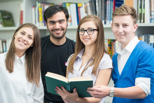 Jovens estudantes felizes estudando na biblioteca da faculdade — Fotografia de Stock