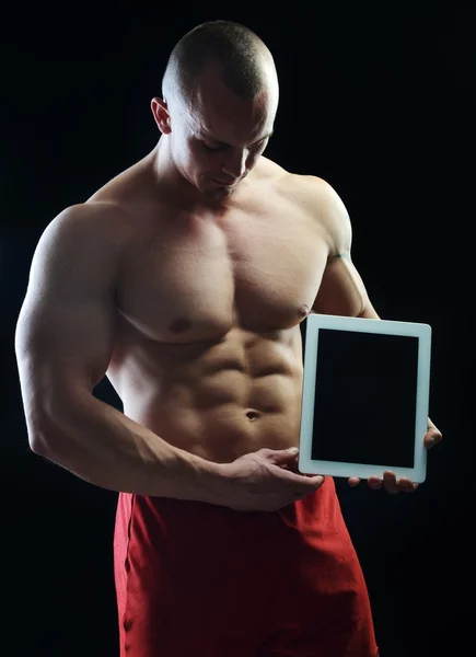 Body builder campione in posa in studio con tablet — Foto Stock