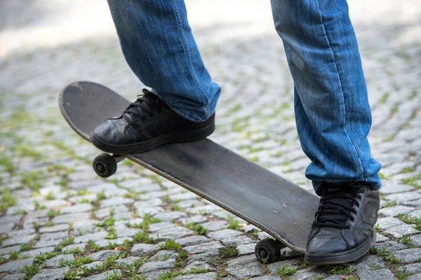 双腿踩着滑板在条铺砌的街道上 — 图库照片