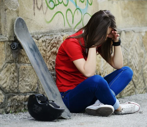 Girl sitting on the street with skateboard — Stock Photo, Image