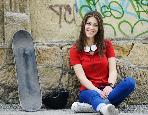 Girl sitting on the street with skateboard