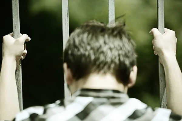 Man in jail holding grates — Stock Photo, Image