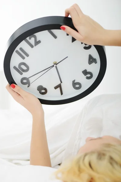 Mujer en la cama en el dormitorio con reloj — Foto de Stock