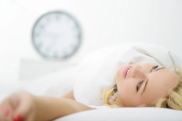 Vrouw op bed in de slaapkamer met horloge — Stockfoto