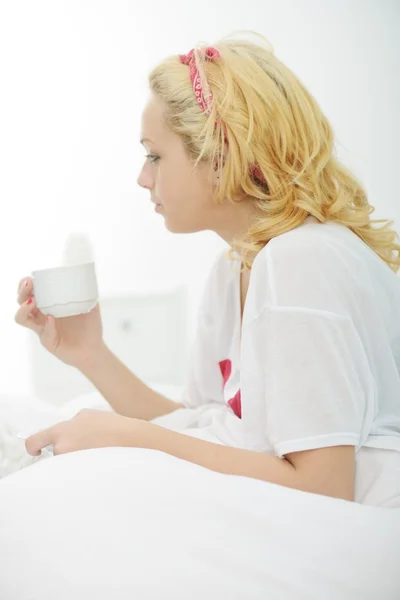 Mujer en la cama en el dormitorio bebiendo café de la mañana — Foto de Stock