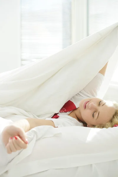 Glücklich blonde Mädchen auf dem Bett im Schlafzimmer — Stockfoto