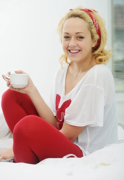 Женщина на кровати в спальне пьет утренний кофе Лицензионные Стоковые Фото