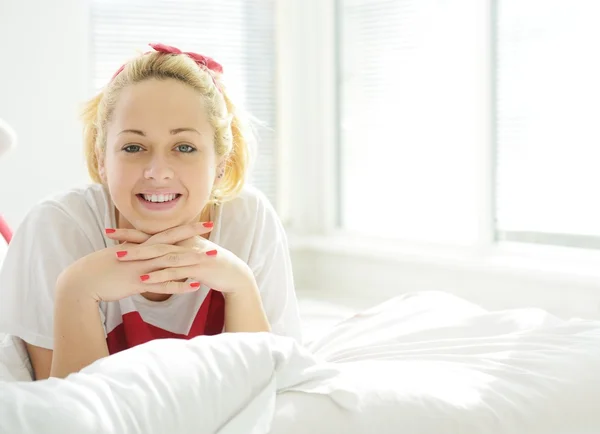 Glad blondin tjej på sängen i sovrummet Stockfoto