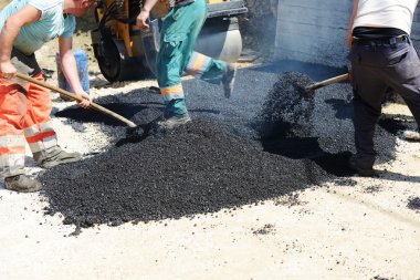 Erkekler kürek ile yol asfaltlama üzerinde çalışma zor