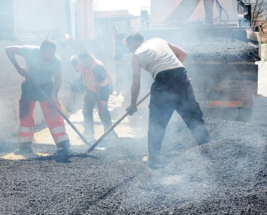 Erkekler kürek ile yol asfaltlama üzerinde çalışma zor