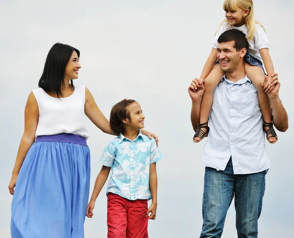 Familia feliz en la naturaleza caminando en el verde prado de verano — Foto de Stock