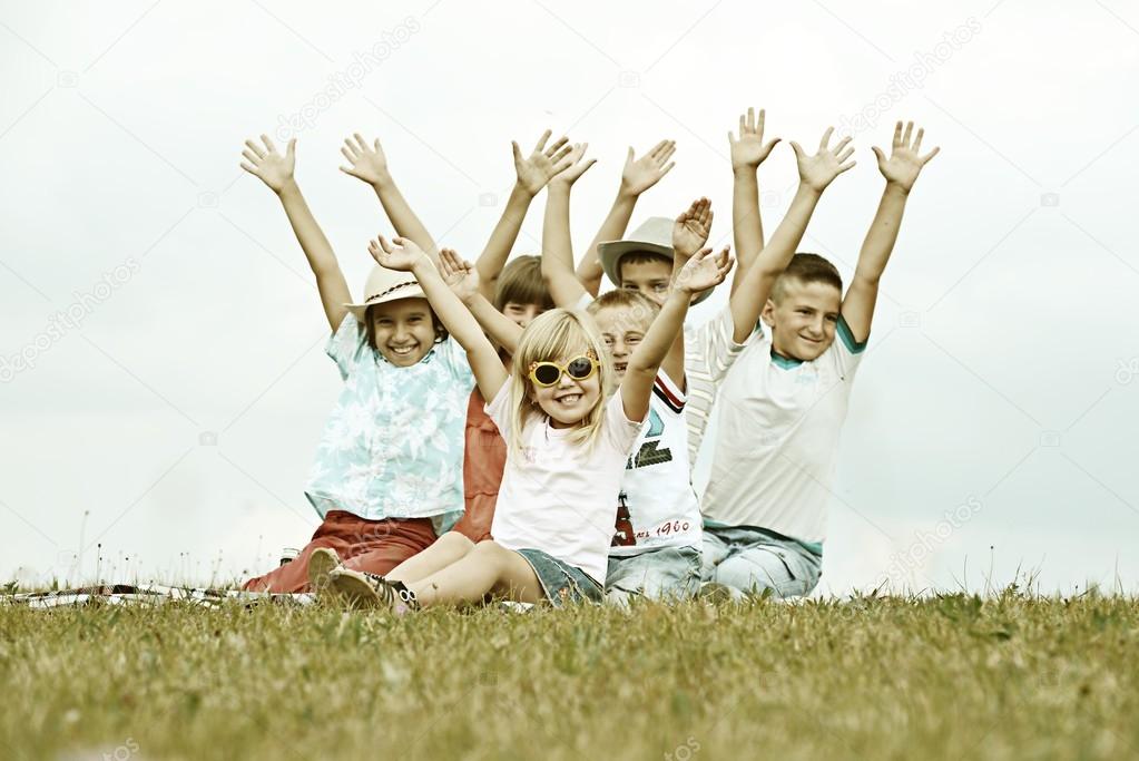 Happy children on summer grass meadow in nature