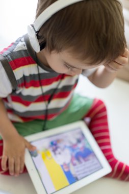 Tablet ve kulaklık kullanarak sevimli küçük çocuk
