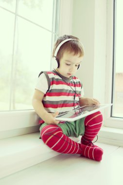 Tablet ve kulaklık kullanarak sevimli küçük çocuk