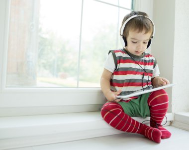 Tablet ve kulaklık kullanarak sevimli küçük çocuk