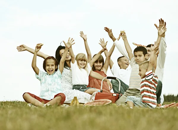 Piknik vakit yeşil çayır on çocuklu aile — Stok fotoğraf