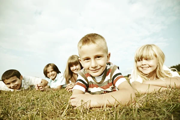 Grupo de crianças felizes no prado de grama de verão — Fotografia de Stock