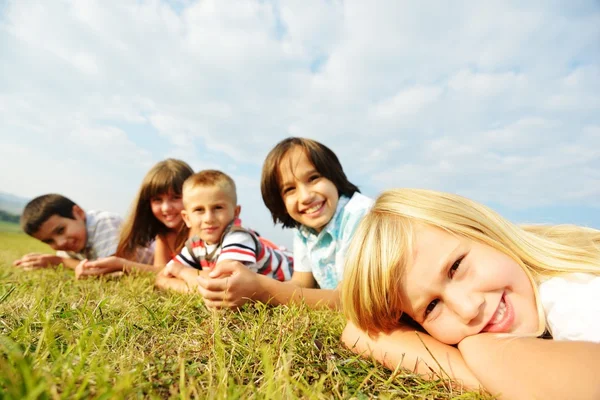 Grupp av glada barn på sommaren gräs äng — Stockfoto