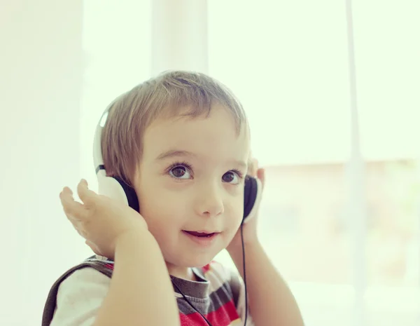 Adorabile bambino a casa ad ascoltare musica con auricolare su h — Foto Stock