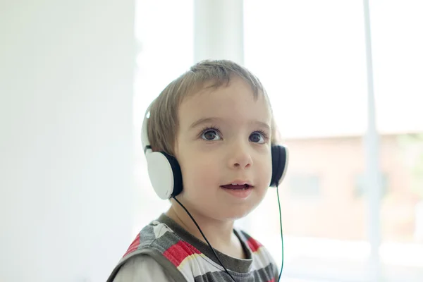 Adorable little boy at home listening to music with headset on h — Stock Photo, Image