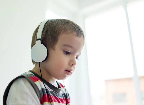 Adorabile bambino a casa ad ascoltare musica con auricolare su h — Foto Stock