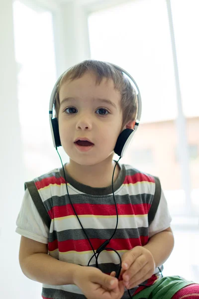 Adorabile bambino a casa ad ascoltare musica con auricolare su h — Foto Stock