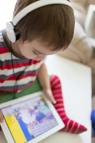 Lindo niño pequeño usando tableta y auriculares —  Fotos de Stock