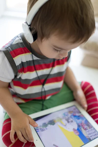 Criança bonito usando tablet e fone de ouvido — Fotografia de Stock