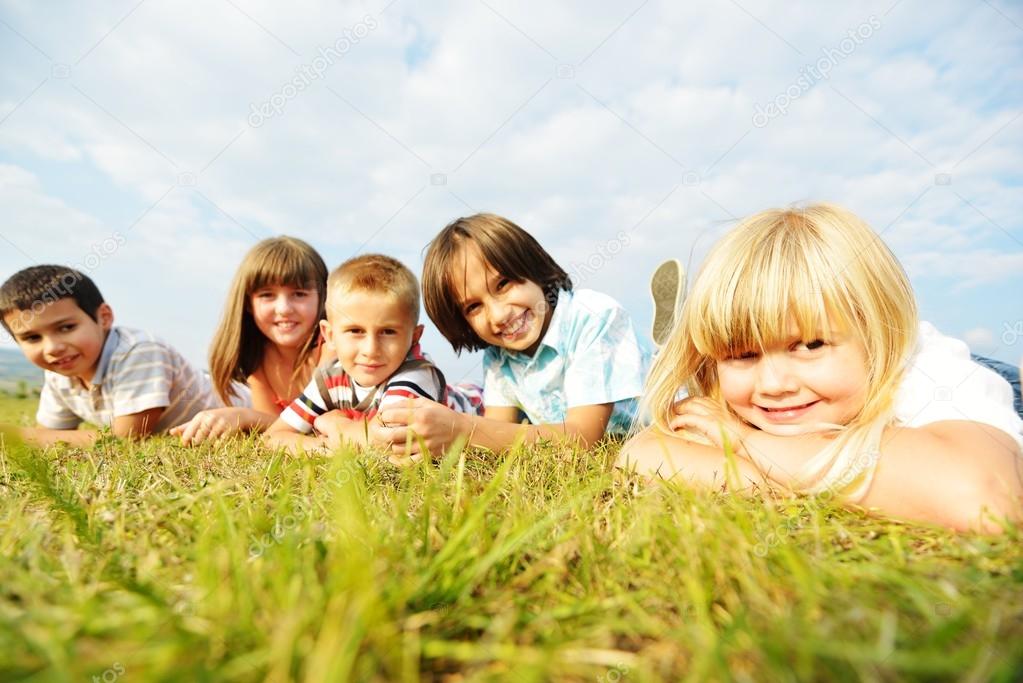 Group of happy children on summer grass meadow