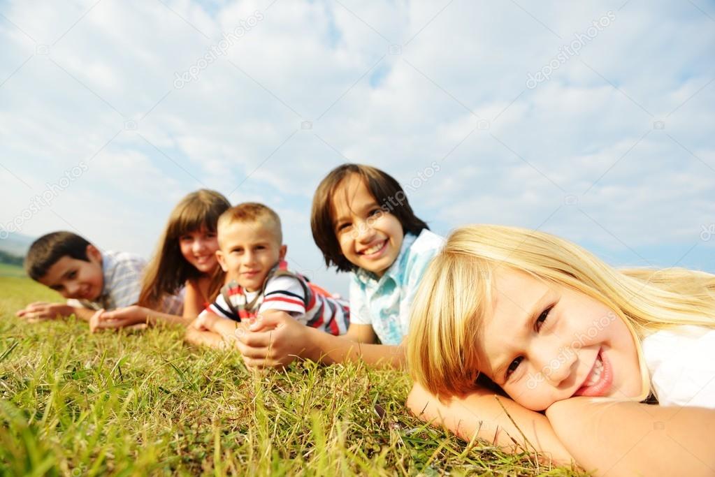 Group of happy children on summer grass meadow