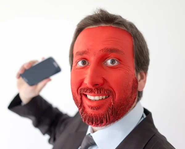 Młody mężczyzna portret z czerwoną twarzą malowane i smartphone — Zdjęcie stockowe